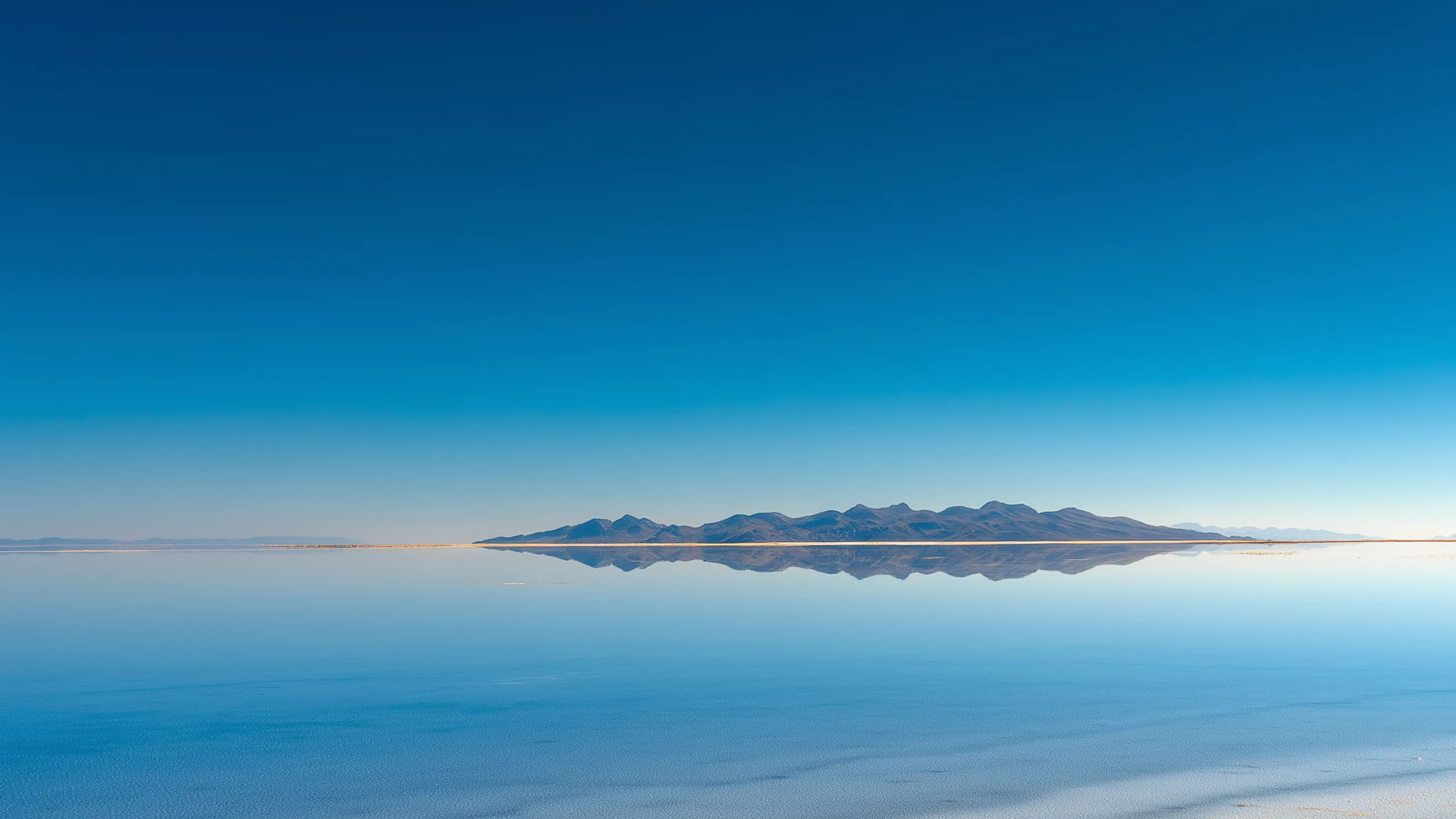 Salar de Uyuni in the morning, clear blue over a still mirror of water